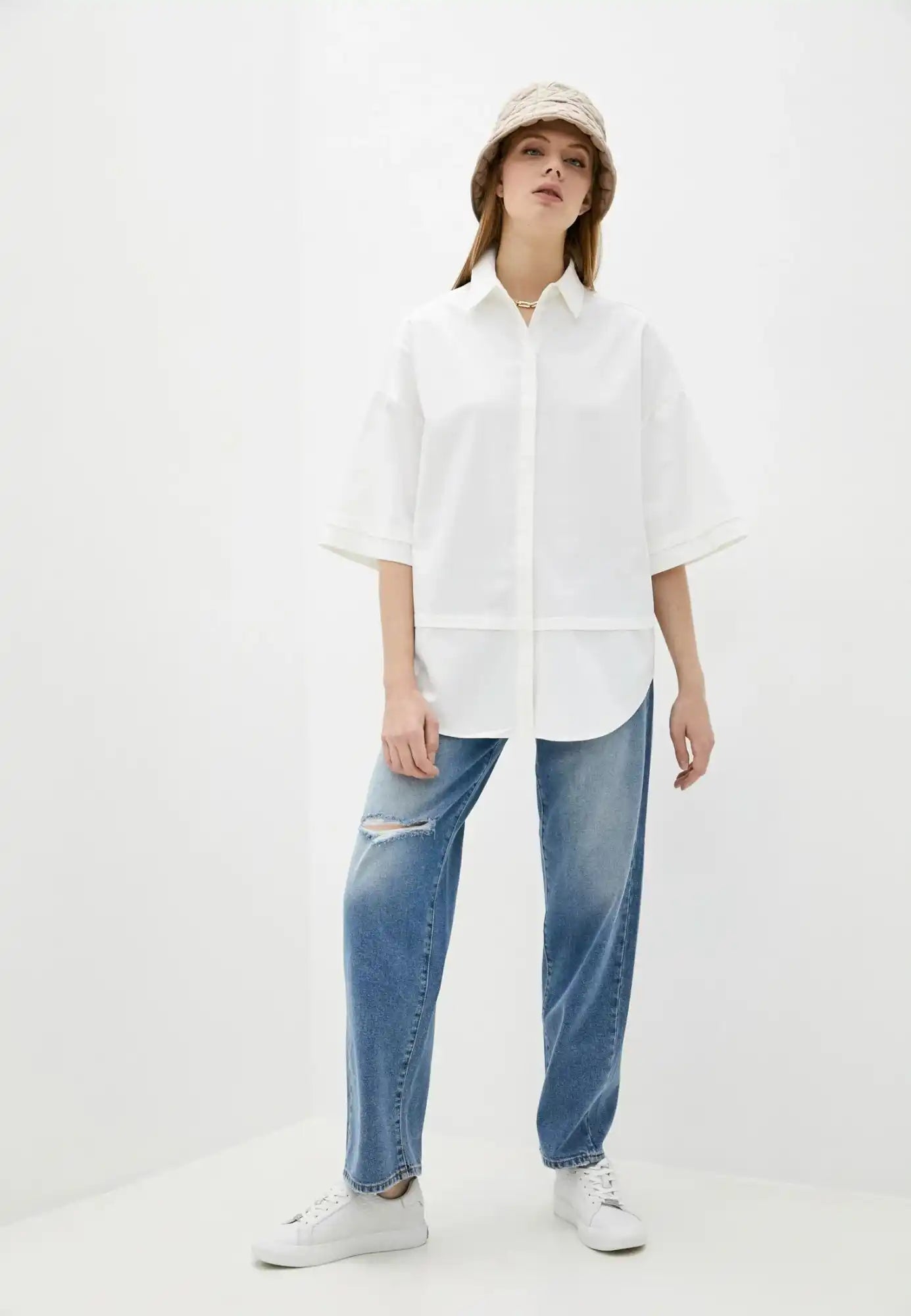 Crisp white oversized button-up shirt with short sleeves paired with distressed blue jeans and white sneakers.
