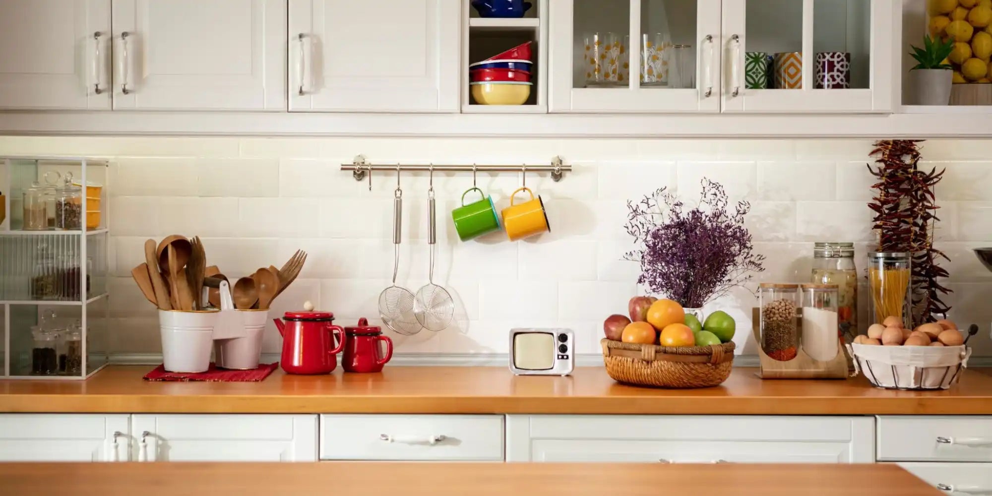 Modern kitchen countertop with white cabinets and wooden butcher block surface.